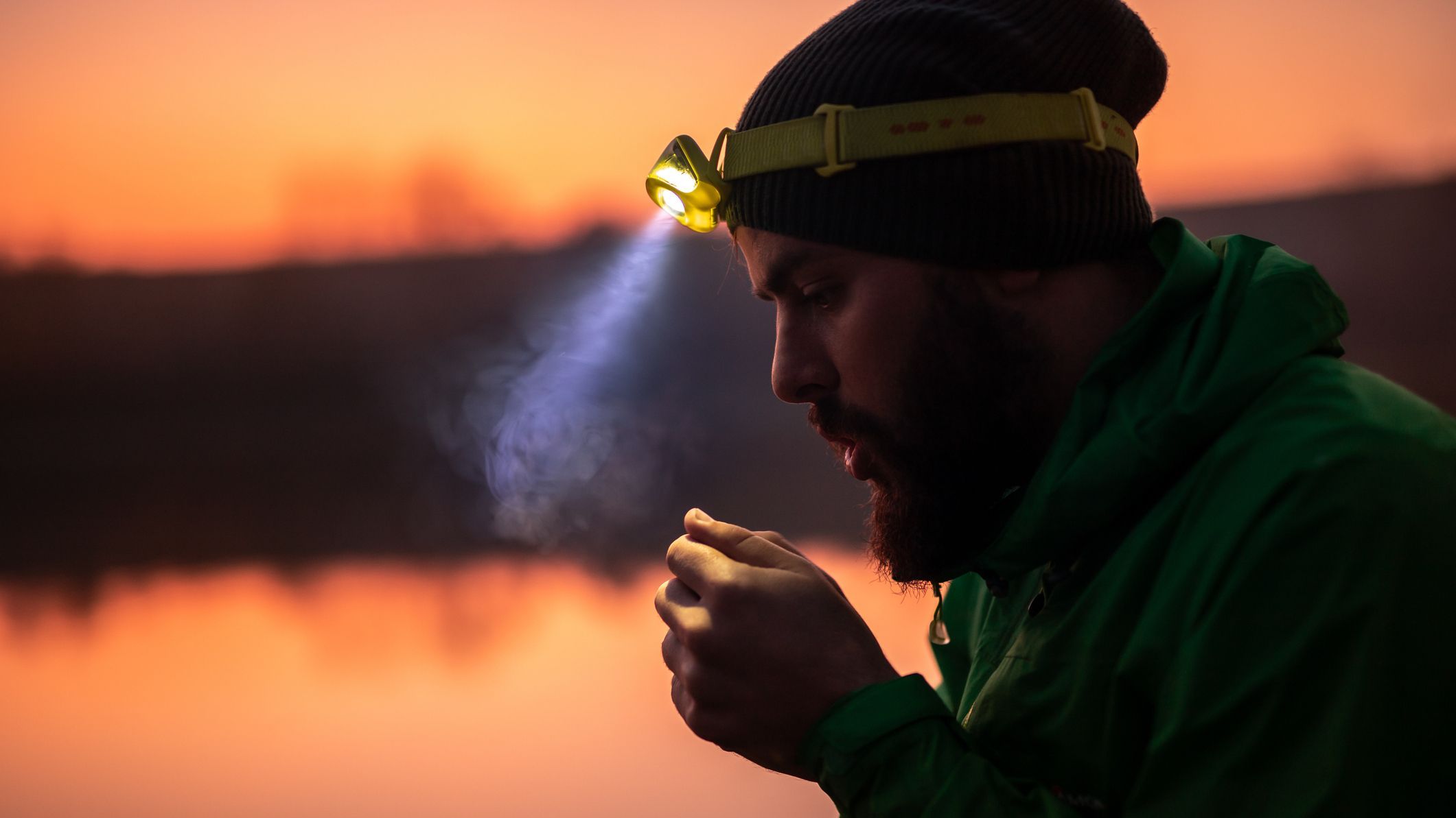 Hiker with headlamp warming up hands in evening