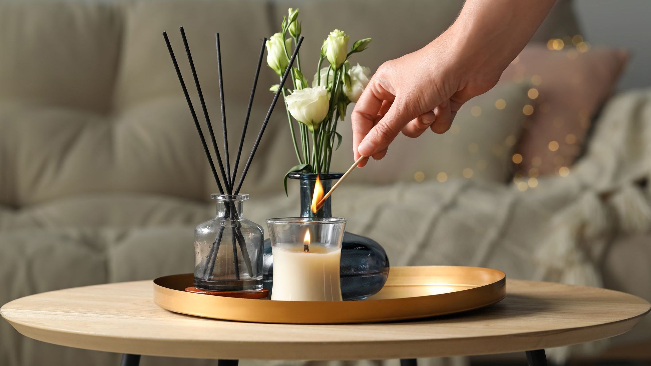 Woman lighting candle at wooden table in living room, closeup