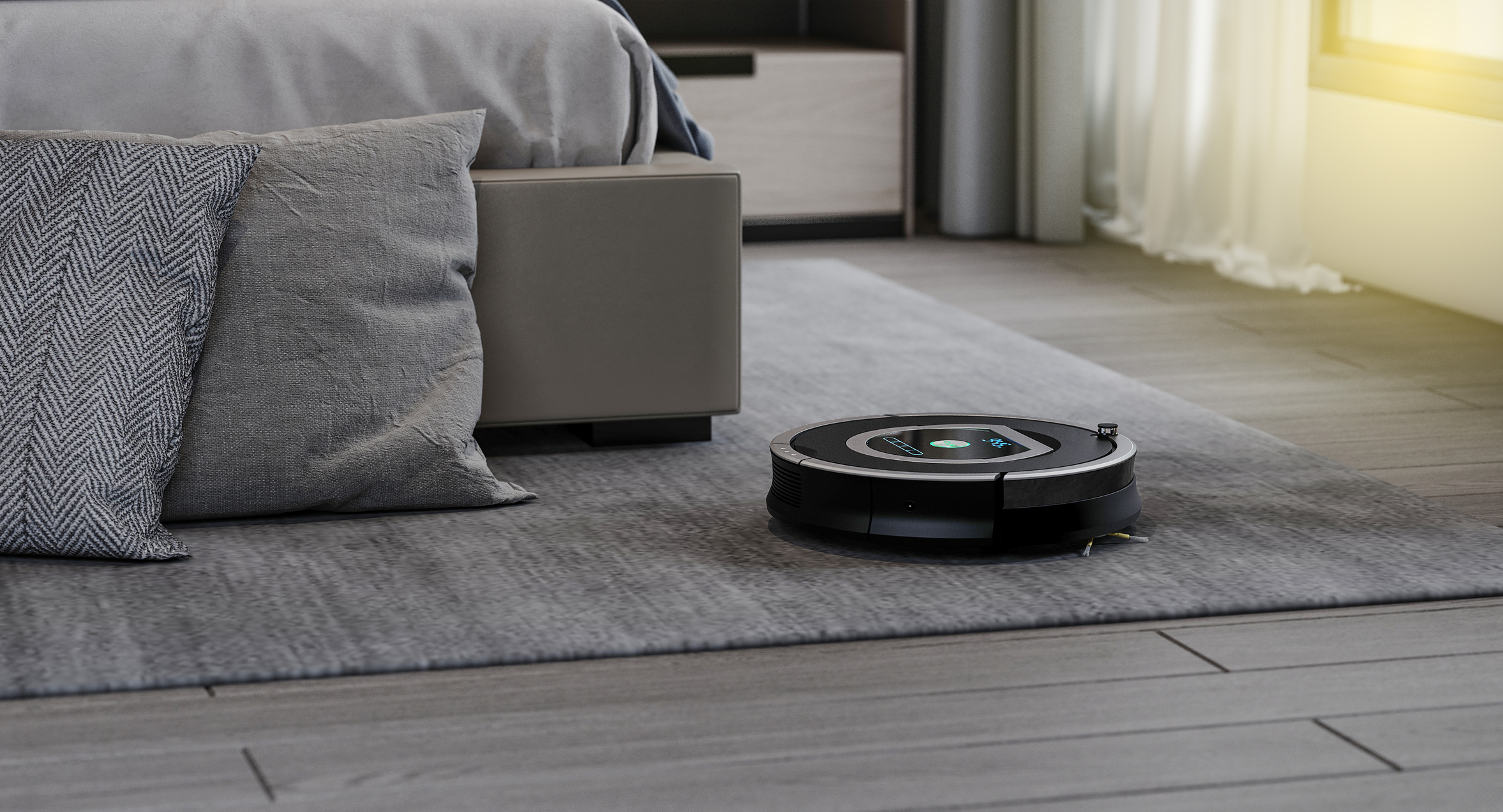 Robotstøvsuger der støvsuger på et tæppe ved en seng