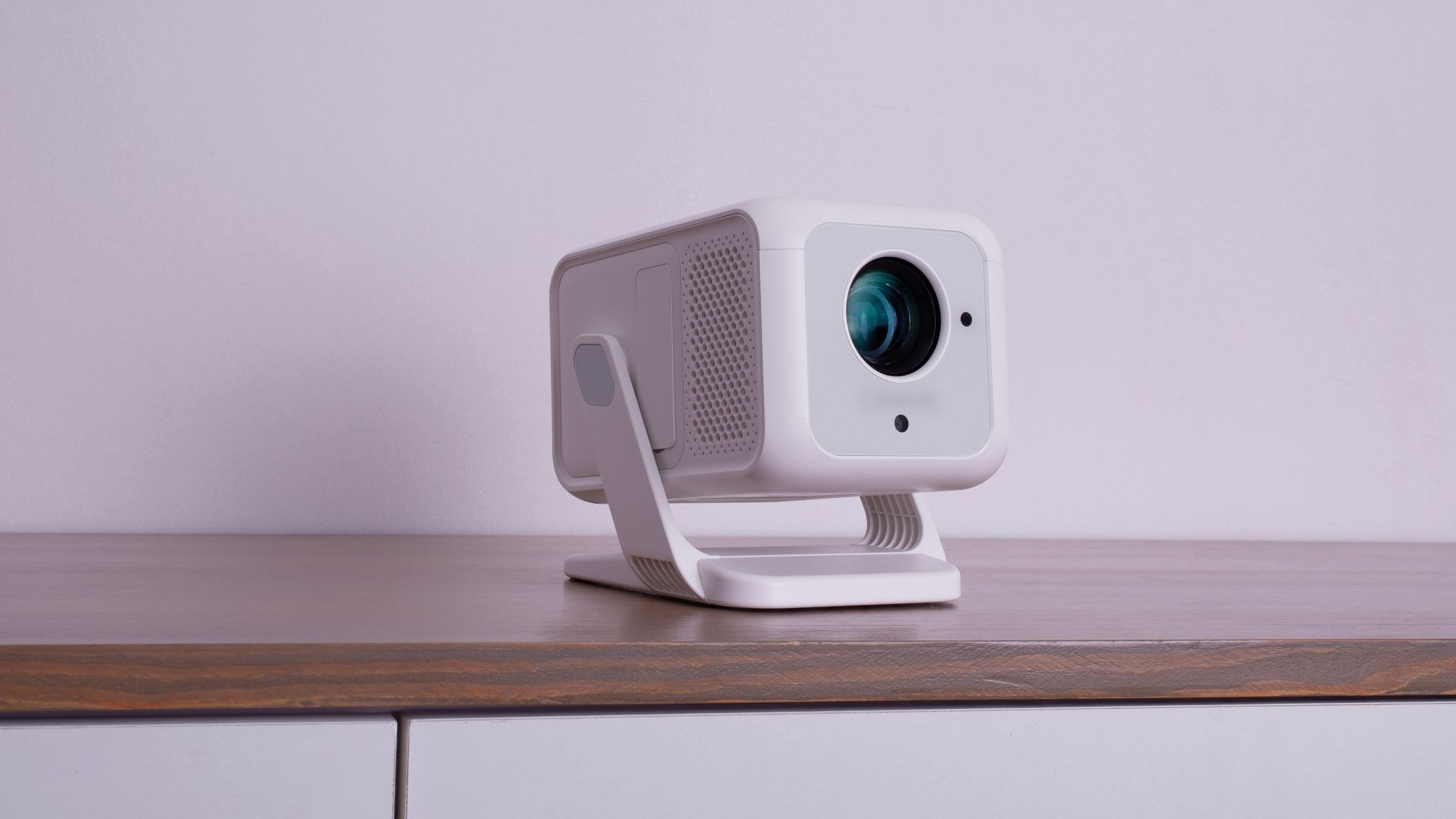 Modern White Portable Home Projector on Stand with Lens Close-Up in Minimalist Interior Setting. 4K Wifi Bluetooth Smart Projector with an a