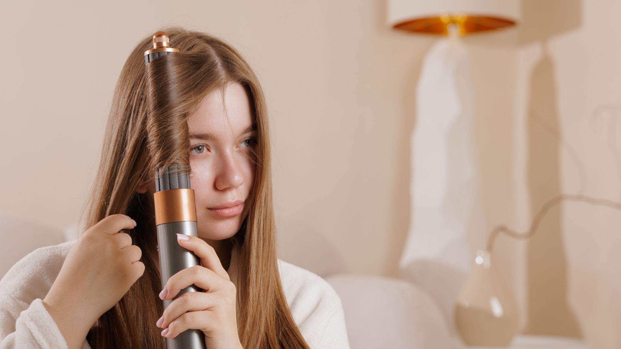 Woman using a modern hair curler at home, styling long hair, beauty routine, innovative device, healthy hair, selfcare
