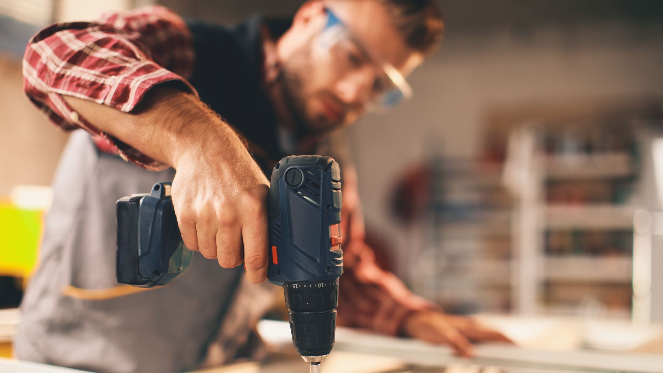 Young man working with drill in the workshop
