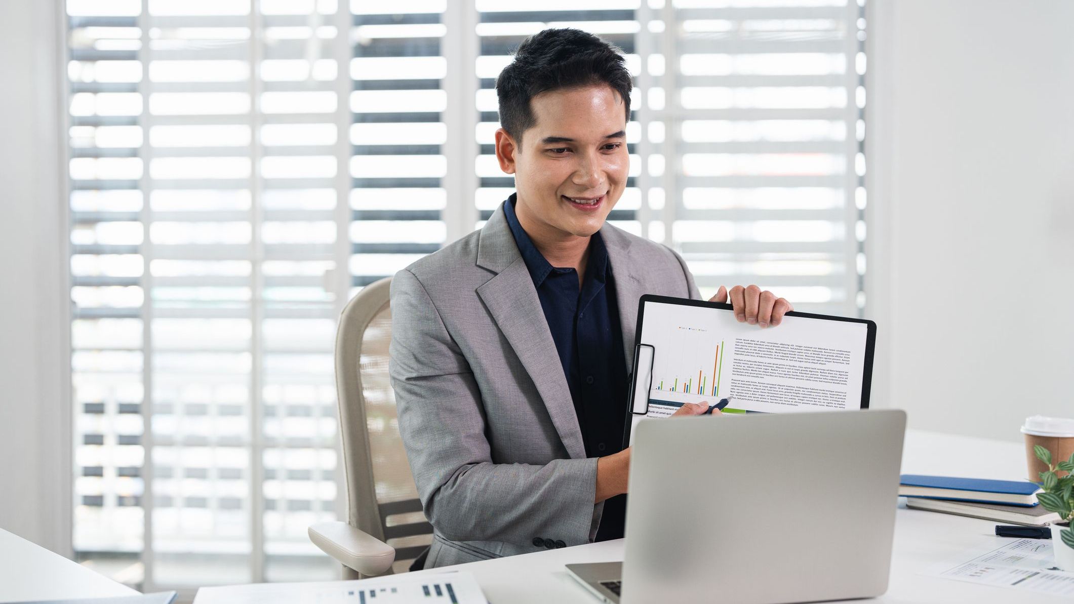 Cheerful smiling man having video call on laptop computer in office.