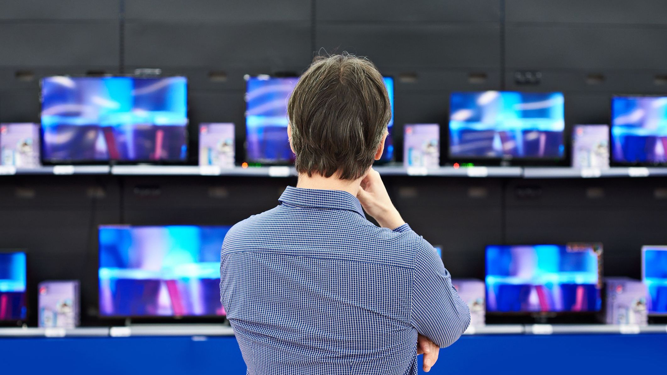 Man looks at LCD TVs in store