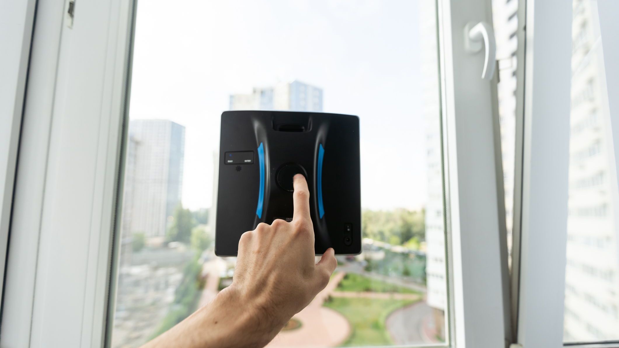 Crop of smart vacuum cleaner washing windows. Home appliance and technology concept