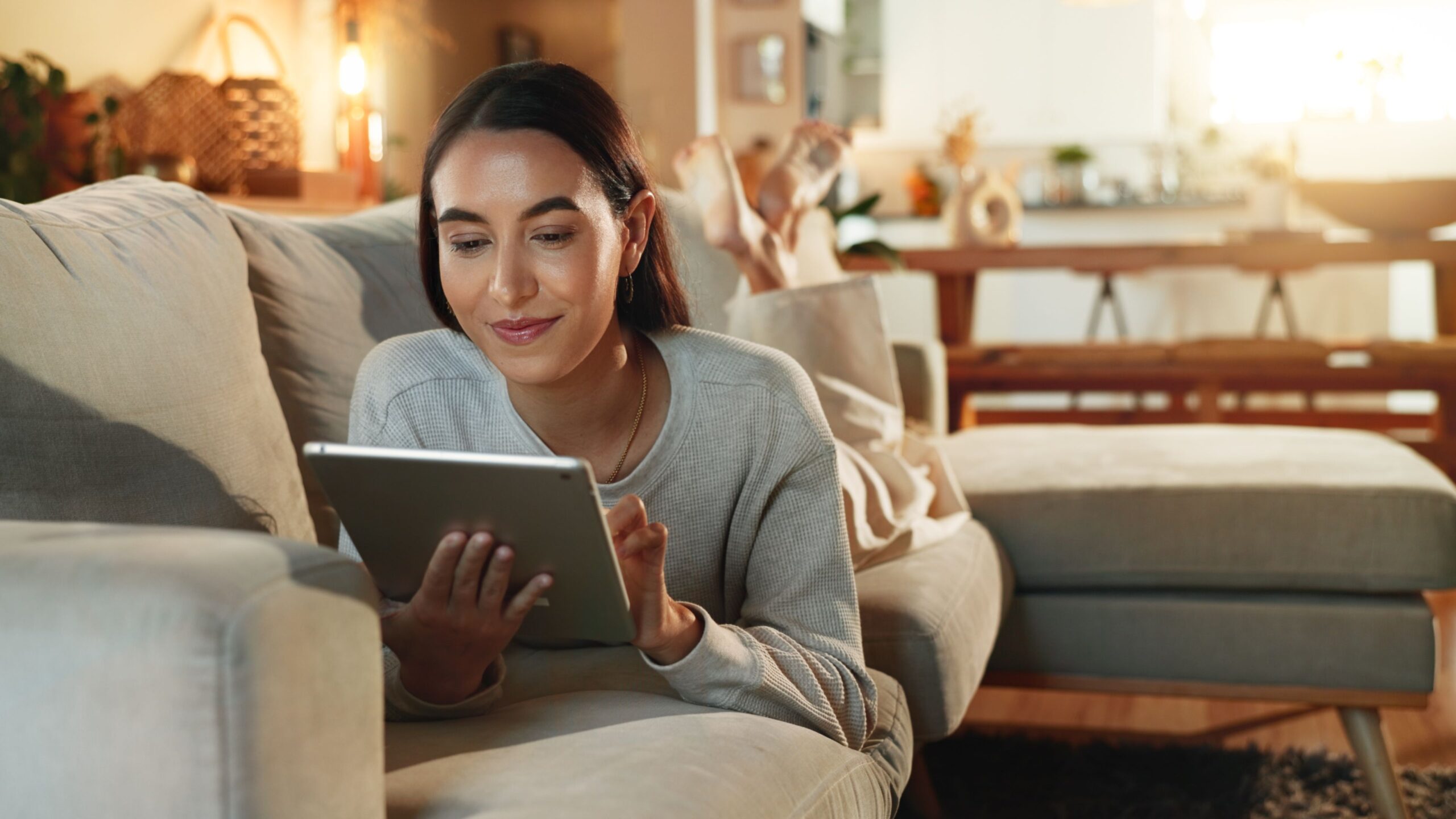 App, relax and tablet with woman on sofa in living room of home for online shopping at night. Ecommerce, smile and technology with happy per