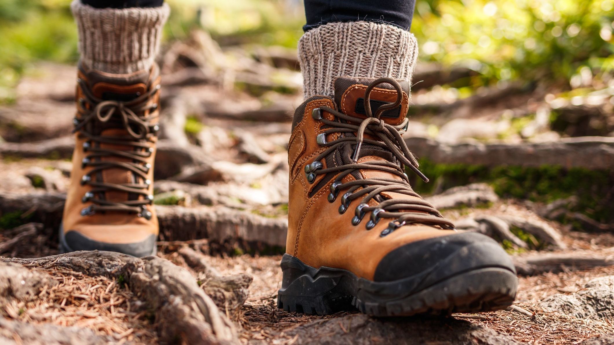 Hiking boot. Legs on mountain trail during trekking in forest. Leather ankle shoes