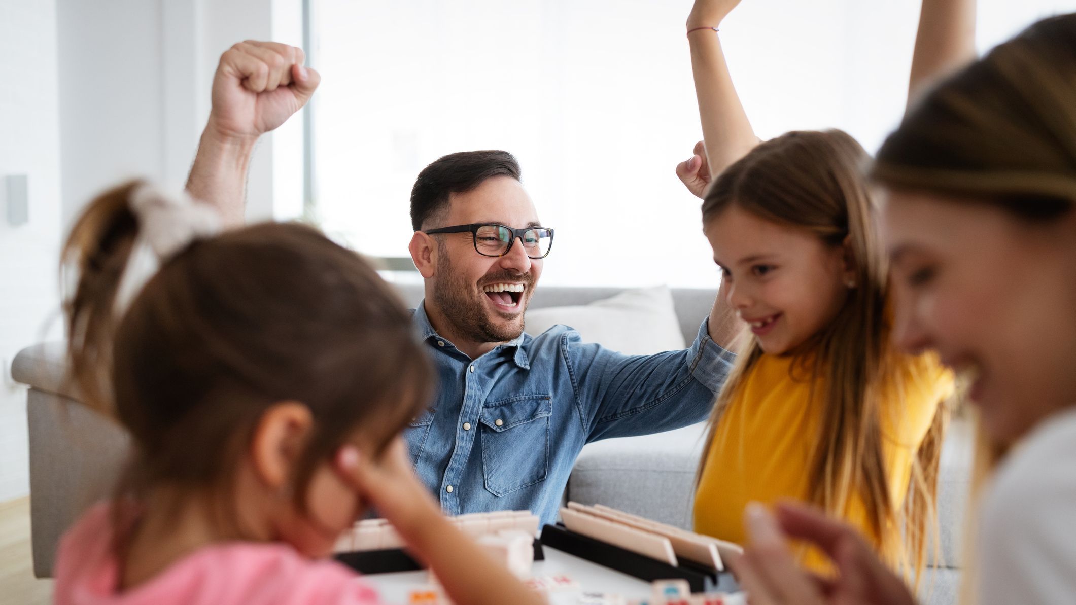 Happy parents and children having fun, playing board game at home