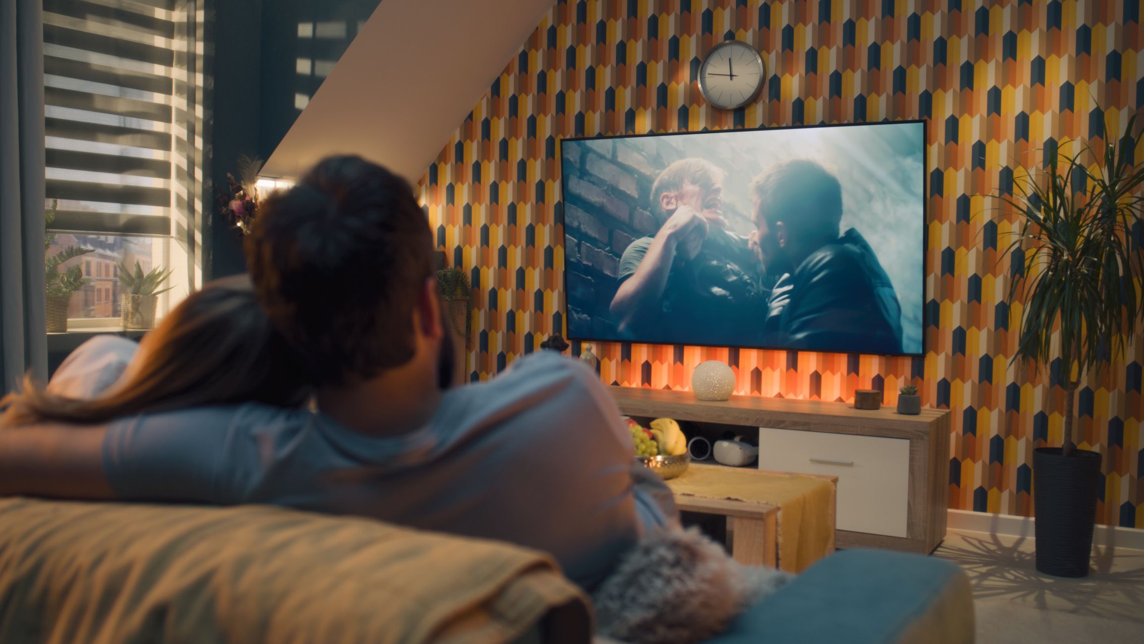 Couple on sofa in living room, watching action movie on TV or criminal blockbuster on streaming service, talking and discussing acting, rest