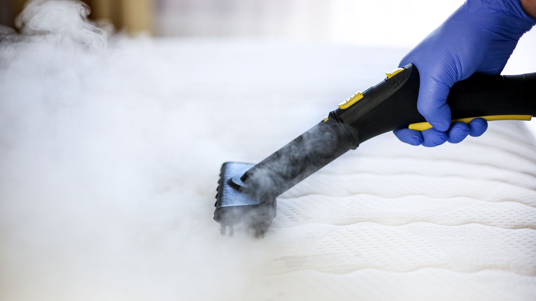 Cleaning and disinfection of the mattress in the bedroom with hot steam. Professional cleaning process