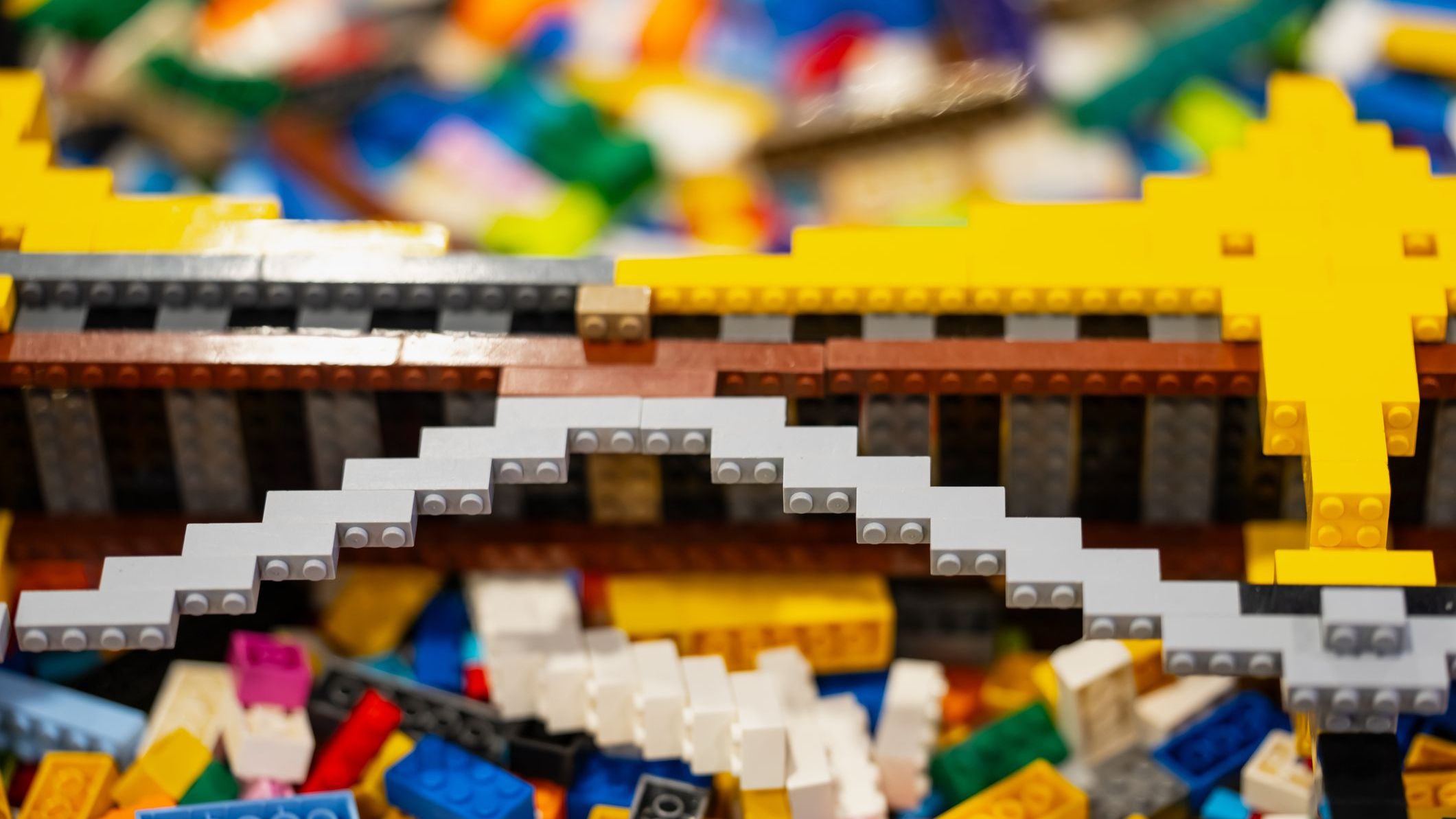 Interlocking toy bricks assembled into a stepped arch above loose construction pieces, illustrating model building and spatial exploration t