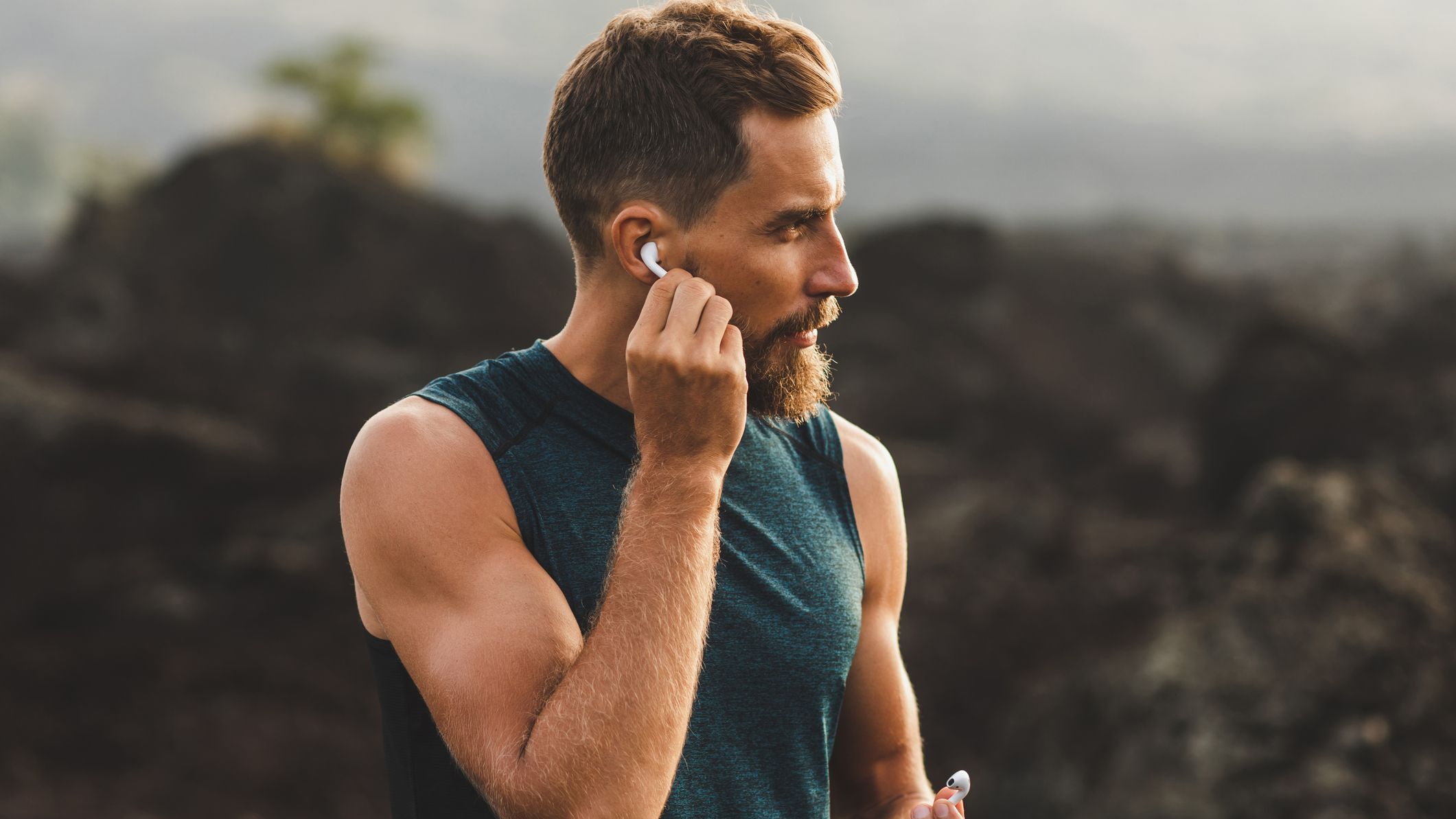 Man using wireless earphones air pods on running outdoors. Active lifestyle concept.