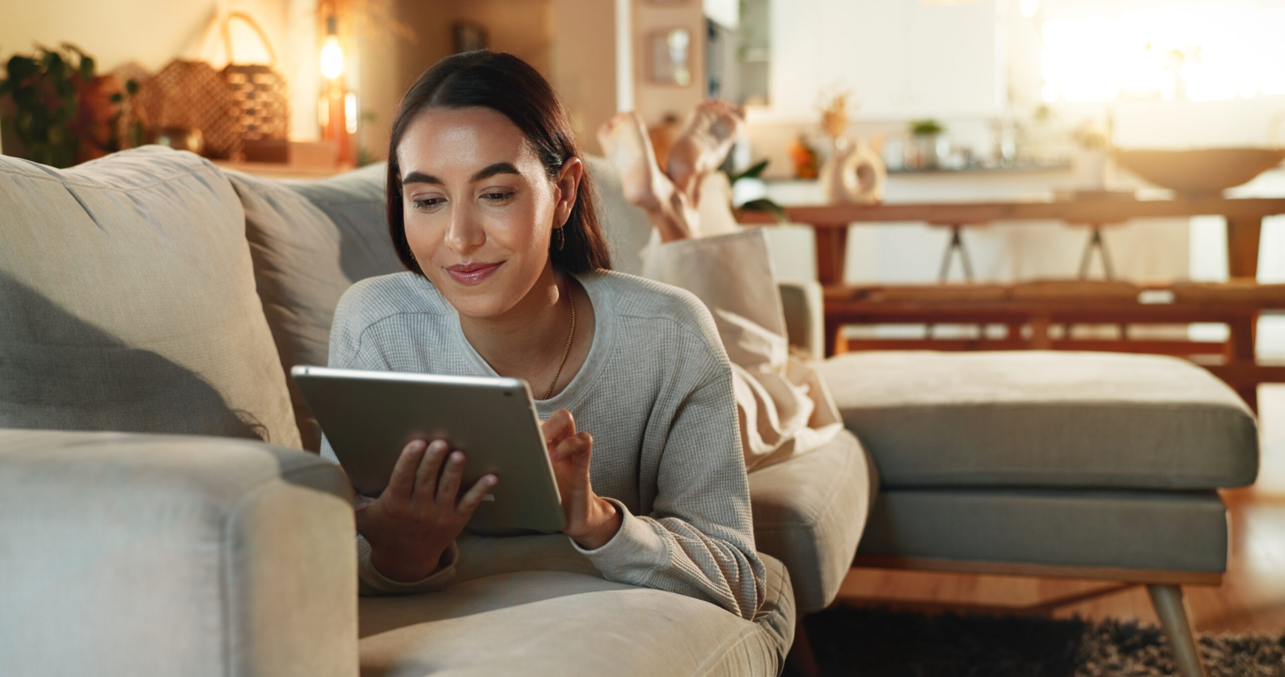 en kvinde ligger i en sofa i en stue og kigger på en ipad