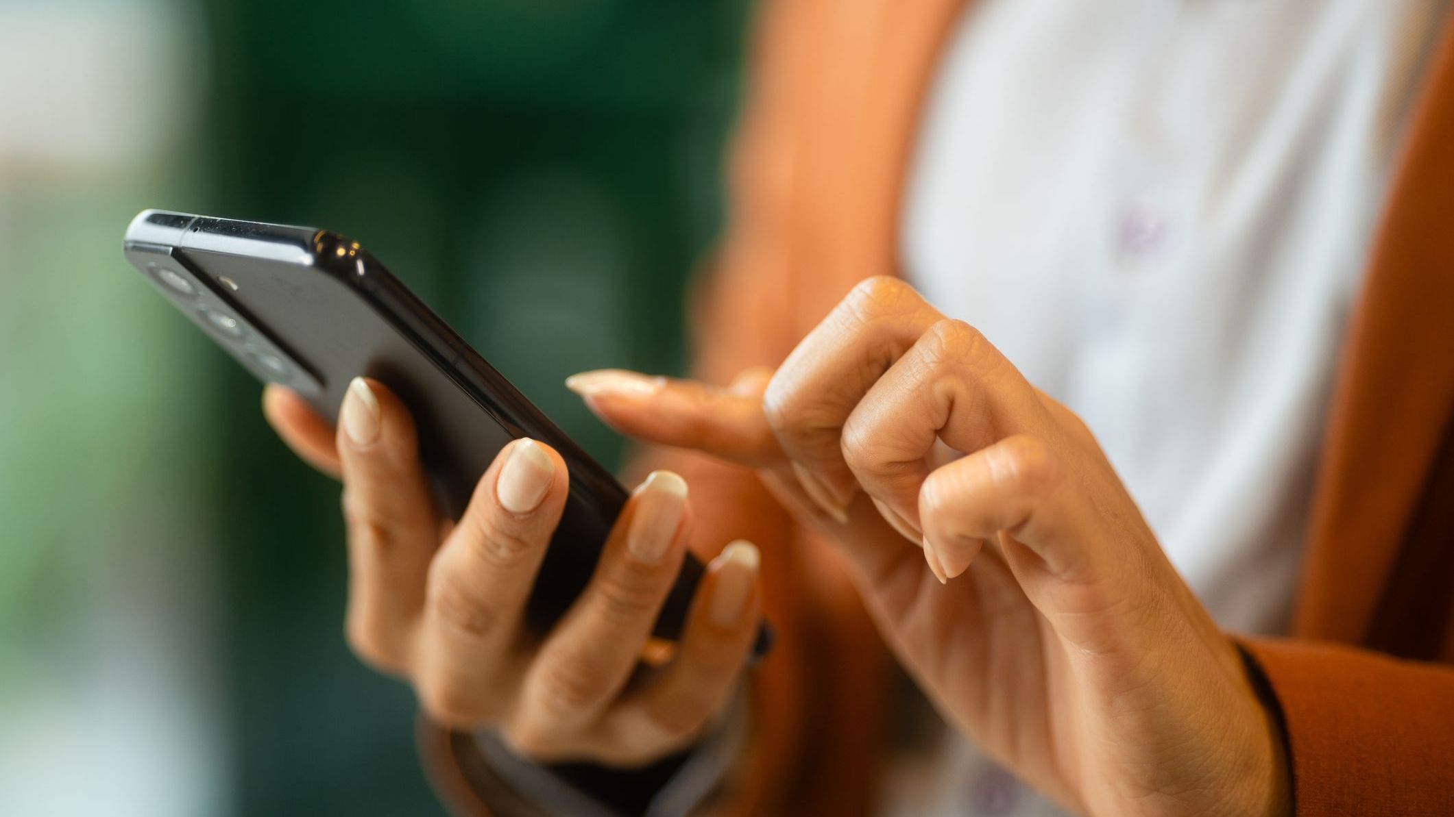 Latin Woman Using Mobile Phone in Cafe. Close-up of Female Hands Typing on Smartphone