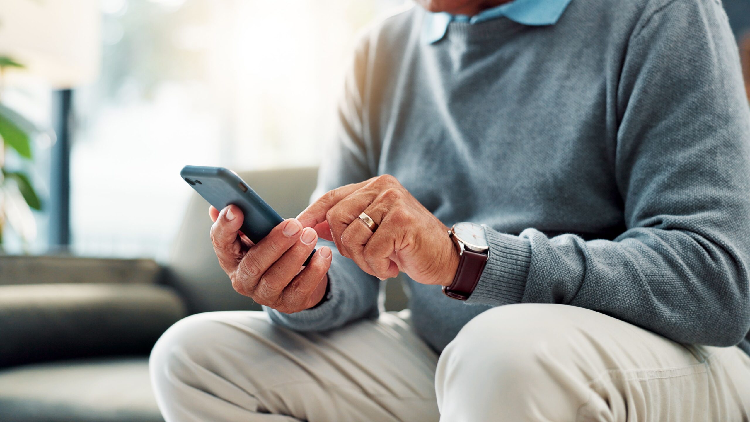 Closeup, male person or elderly user browsing with mobile smartphone for connection or network