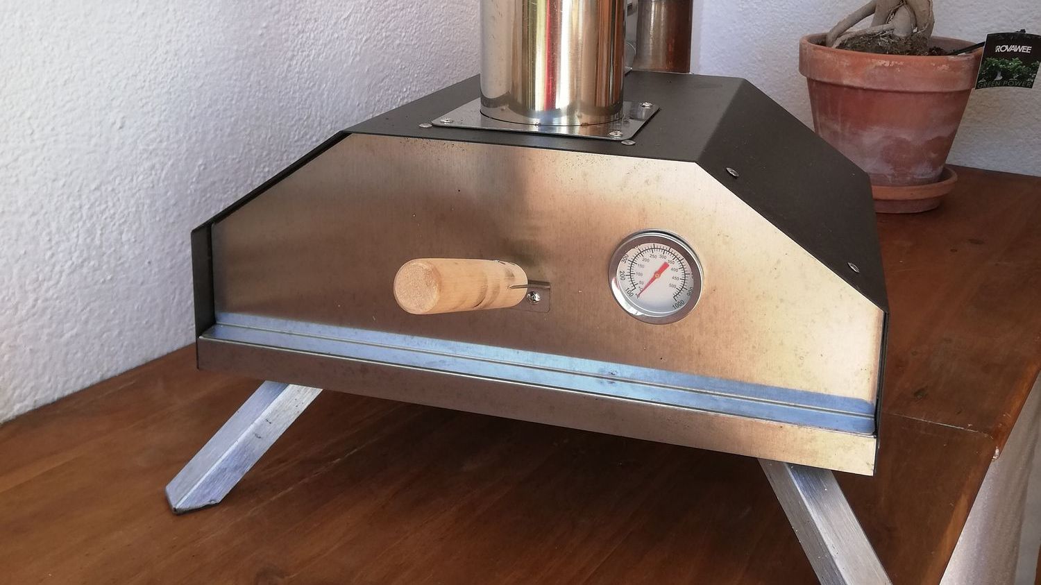 shot of a silver pizza oven on a wooden table in the kitchen