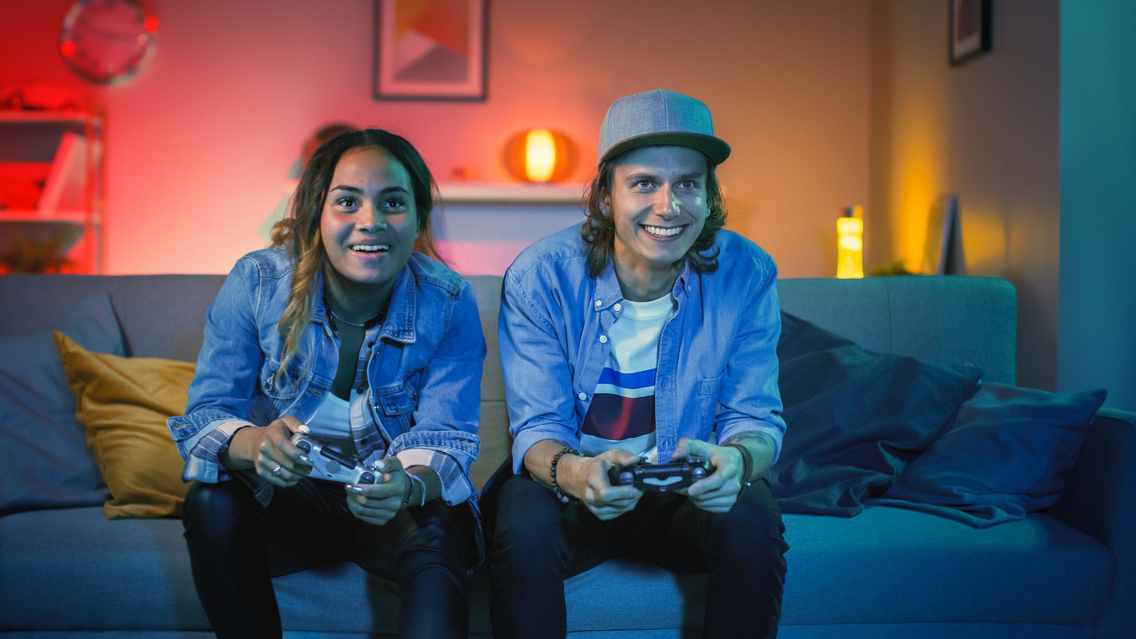 Excited Gamer Girl and Young Man Sitting on a Couch and Playing Video Games on Console. They Plays with Wireless Controllers