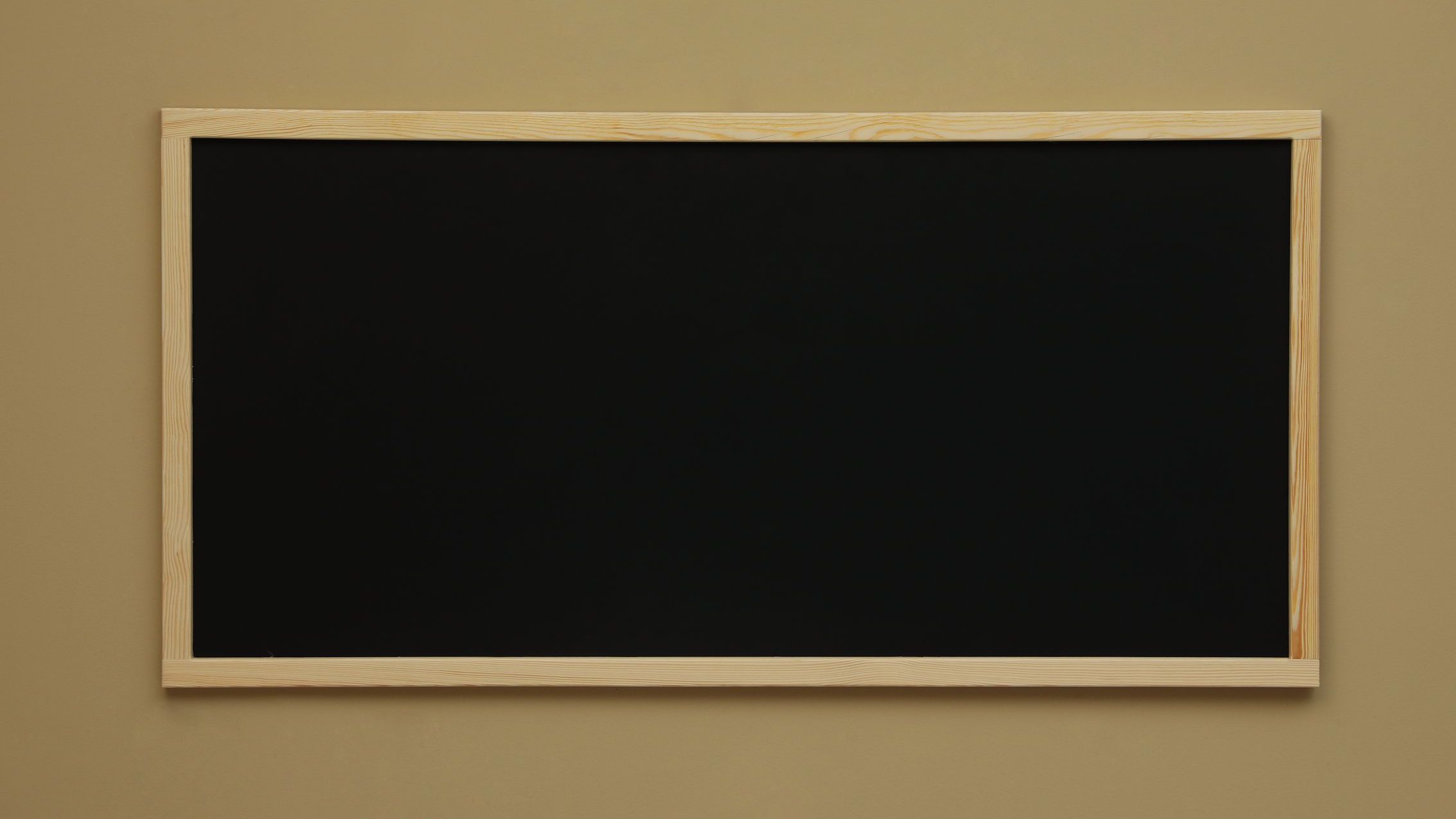 Clean black chalkboard hanging on beige wall